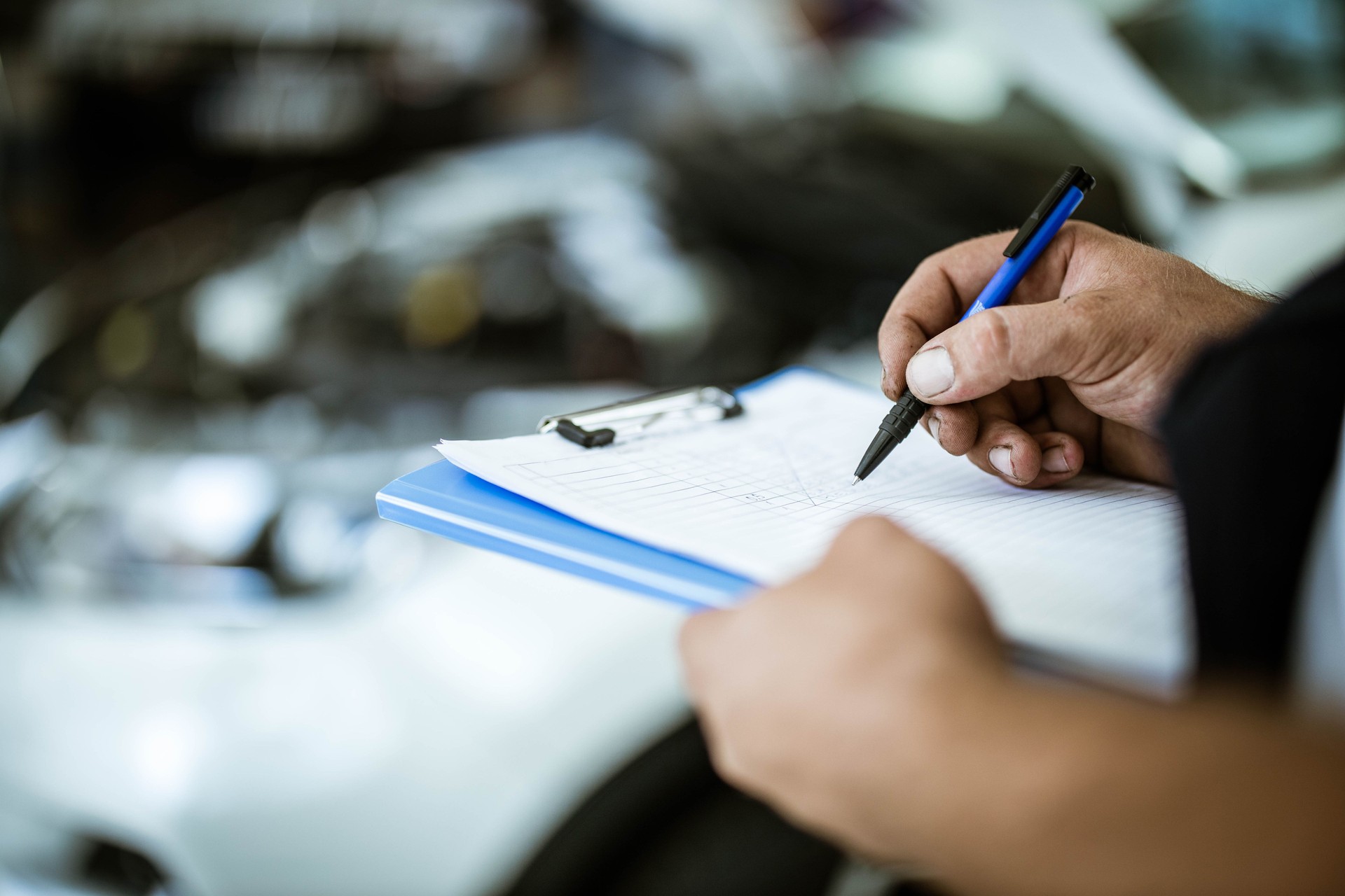Close up of unrecognizable auto mechanic going through checklist.